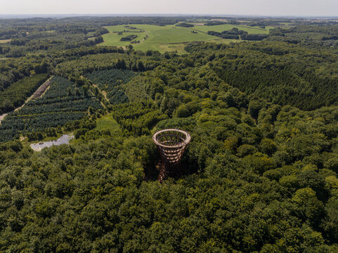Aerial view of Camp Adventure observation tower rising above the dense green forest canopy in Ronnede, Denmark.