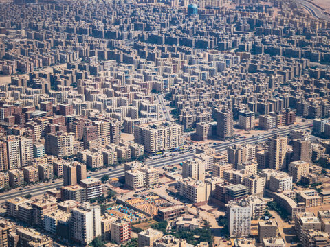 Aerial view of the dense urban landscape of Cairo, featuring numerous apartment buildings, a major highway, and city streets in Cairo, Cairo Governorate, Egypt.