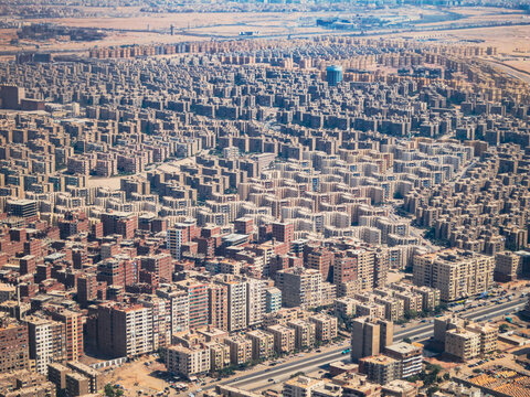 Aerial view of the dense urban landscape of Cairo featuring rows of residential apartment buildings and busy streets in Cairo, Cairo Governorate, Egypt.