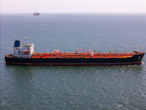 Aerial view of a large chemical container vessel sailing on the calm blue Atlantic Ocean with a distant ship on the horizon Cascais, Lisboa, Portugal.