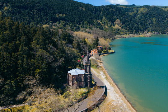 Aerial view of Ermida de Nossa Senhora das Vitorias situated on the shore of Furnas Lake surrounded by dense forest and lush vegetation in Furnas, Acores, Portugal.