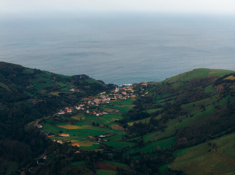 Aerial view of Flores Island with its charming village nestled in a lush green valley surrounded by rolling hills and the Atlantic Ocean, Azores, Portugal.