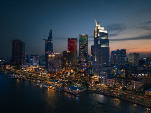 Aerial view of the illuminated Ho Chi Minh City skyline along the Saigon River at dusk, featuring modern skyscrapers and glowing city lights in Ho Chi Minh City, Ho Chi Minh, Vietnam.