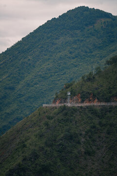 View of a watchtower on a mountain ridge with lush green slopes and a cloudy sky in Vietnam.