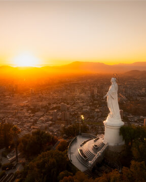 Aerial view of the Virgin of the Immaculate Conception statue overlooking the city of Santiago at sunset with golden light in Providencia, Santiago Metropolitan, Chile.