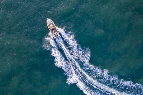 Aerial view of a motorboat cruising through the deep blue waters of Marina Herzliya, leaving a white wake behind it in Herzliya, Tel Aviv District, Israel.