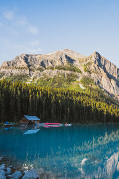 View of Lake Louise with its turquoise water reflecting the surrounding pine forest and rugged mountain peaks under a clear blue sky in Lake Louise, Alberta, Canada.