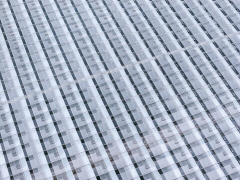 Aerial view of an industrial scale greenhouse with repetitive glass panels and metal structures in Poland.