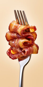 Crispy bacon wrapped appetizers stacked on a fork against beige background