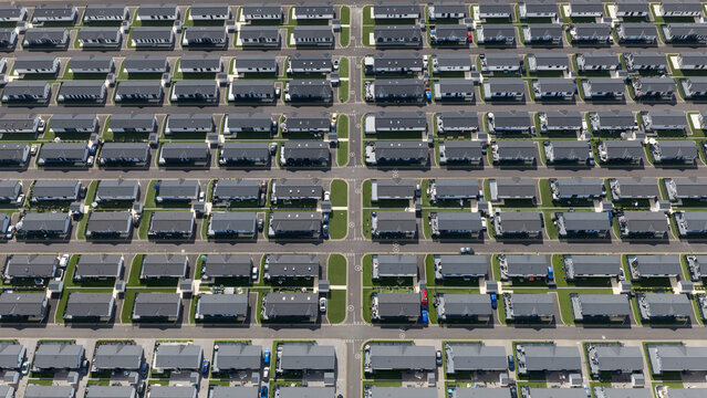 Aerial view of the organized rows of modern homes with dark roofs and green lawns at Sandy Bay Residential Resort in Canvey Island, England, United Kingdom.