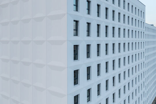 Aerial view of the modern white facade of a building featuring a repeating geometric texture and numerous windows in Krakow, Lesser Poland Voivode, Poland.