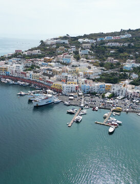 Aerial view of the colorful harbor of Ponza with docked ferries, yachts, and boats along the waterfront, surrounded by hillside buildings in Ponza, Lazio, Italy.