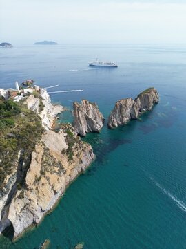 Aerial view of the Faraglioni di Lucia Rosa rock formations rising from the turquoise Tyrrhenian Sea near the rugged coastline of Ponza, Lazio, Italy.