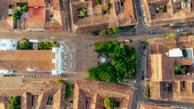 Aerial view of the central plaza and historic church surrounded by colonial buildings with terracotta rooftops and lush trees in Suchitoto, Cuscatlan Department, El Salvador.