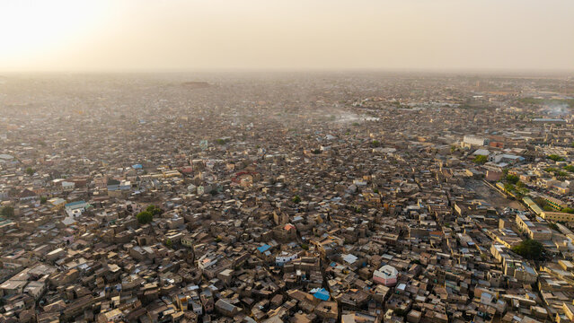 Aerial view of the dense urban landscape of Kano, featuring closely packed traditional rooftops and buildings under a hazy sky in Kano, Kano, Nigeria.