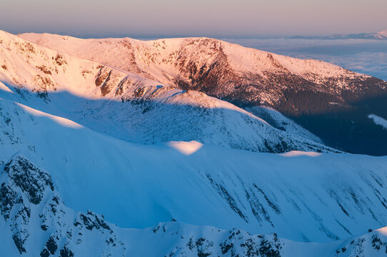 Aerial view of the snow-covered slopes of Dumbier in the Low Tatras mountains illuminated by golden hour light in Liptovsky Jan, Zilina Region, Slovakia.