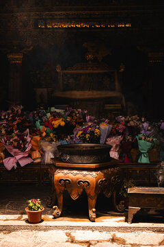 View of a traditional altar with a bronze incense burner and vibrant floral offerings inside a temple in Lhasa, Tibet, China.