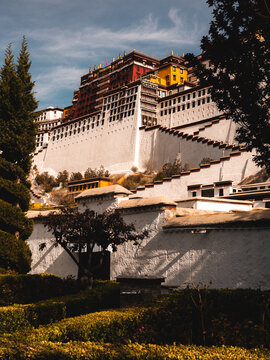 View of the Potala Palace with its iconic white walls and red and yellow architecture set against a clear blue sky in Lhasa, Tibet, China.