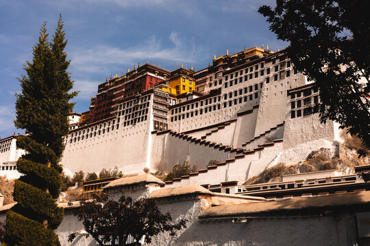 View of the Potala Palace with its iconic white and red walls and tiered architecture under a clear blue sky in Lhasa, Tibet, China.