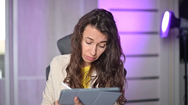 Focused female artist sketching a digital drawing using a stylus and tablet for a creative design in her studio project