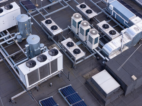 Aerial view of industrial HVAC cooling units and ventilation systems on a flat rooftop with solar panels, Gdansk, Pomeranian Voivodeship, Poland.