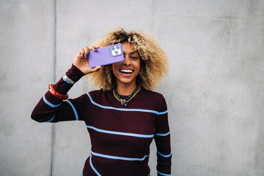 Smiling woman holding phone to her eye