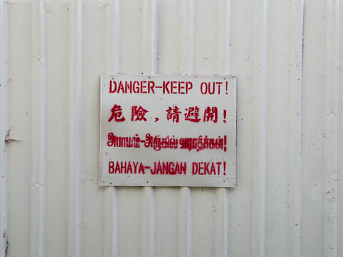 Multilingual Danger Keep Out Sign on White Construction Hoarding, Singapore