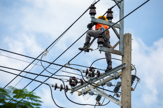 Rear view of Electrician Worker Climbing High Power Pole for Maintenance Work