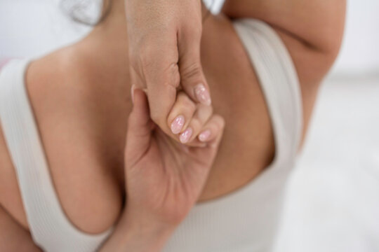 Upper body stretch performed by young woman wearing white activewear top holding hands behind back