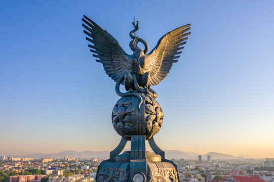 Aerial view of the bronze eagle sculpture atop the Monumento a la Independencia, set against a clear sky above the urban landscape. Ciudad de Mexico, Ciudad de Mexico, Mexico.