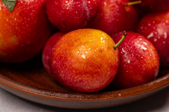Fresh red and yellow plums with water drops in bowl