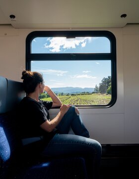 Mujer sentada en un asiento de tren mirando y disfrutando del paisaje a trav&eacute;s de la ventana. Viajando, transporte