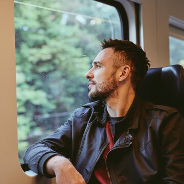 Hombre sentado en un asiento de tren mirando y disfrutando del paisaje a trav&eacute;s de la ventana. Viajando, transporte