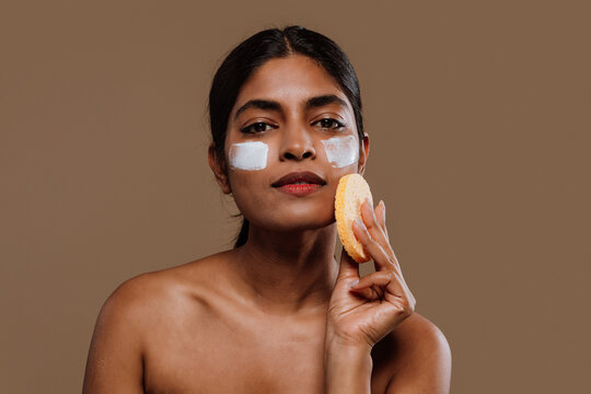  Young woman applying moisturizer on face