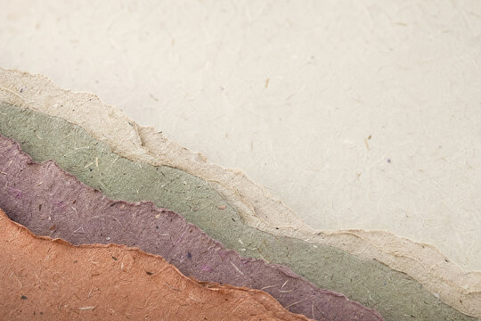 Handmade recycled paper with torn edges, textured mulberry paper layers in earth tones, organic craft paper background