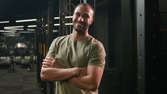 Friendly African American man male fitness trainer inviting people to workout in gym come here hand gesture smiling guy ethnic athlete welcoming viewers while posing with crossed arms in sports club