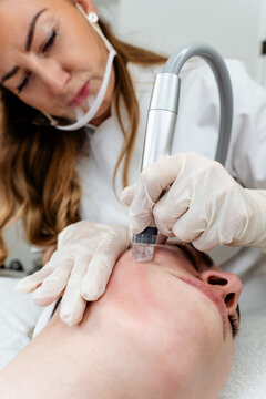 Specialized skincare professional using modern aesthetic equipment for facial rejuvenation therapy on a client receiving clinical beauty care.