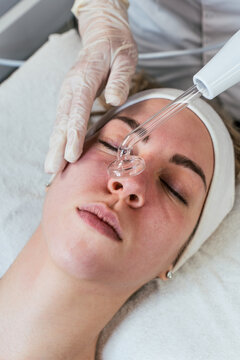 Cosmetologist using frequency darsonval device for skin rejuvenation, acne treatment, and anti-aging therapy in a modern medical spa.