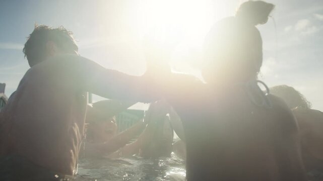 Friends high-fiving in a steaming outdoor hot tub during a social spa celebration