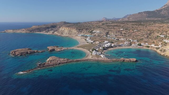 Drone footage approaching from above to reveal the unique setting of Lefkos Beach in Karpathos, featuring crystal-clear waters, golden shores, and the island's spectacular coastal landscape.