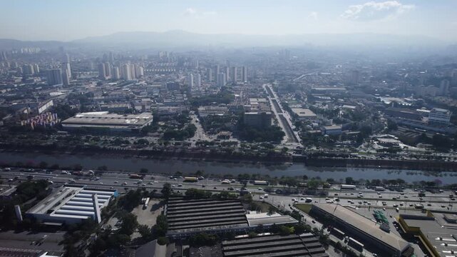 Drone traveling left showing, by far, the Tiet&ecirc; River, and Tiet&ecirc; road with the S&atilde;o Paulo skyline