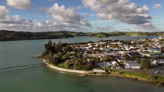 Aerial view of coastal Raglan town peninsula and footbridge over estuary during sunset in New Zealand