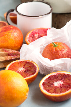 Close-up of fresh sliced blood oranges and halved oranges on a table for making orange juice