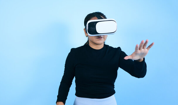 young Mexican woman using virtual reality glasses on blue background in Mexico Latin America, portrait of latina girl in technology concept