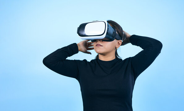 young Mexican woman using virtual reality glasses on blue background in Mexico Latin America, portrait of latina girl in technology concept