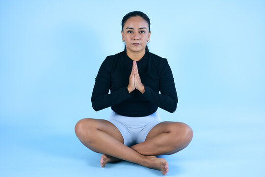 young mexican woman meditating or doing yoga with copy space on blue background in Mexico Latin America, latina brunette woman om meditation mood 