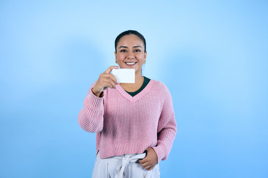 young mexican brunette woman holding a blank card with copy space on blue background in Mexico Latin America, portrait of latina girl with copy space 