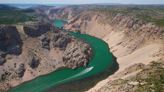 Breathtaking aerial view of Zrmanja River canyon meander with a speedboat navigating emerald waters in Croatia
