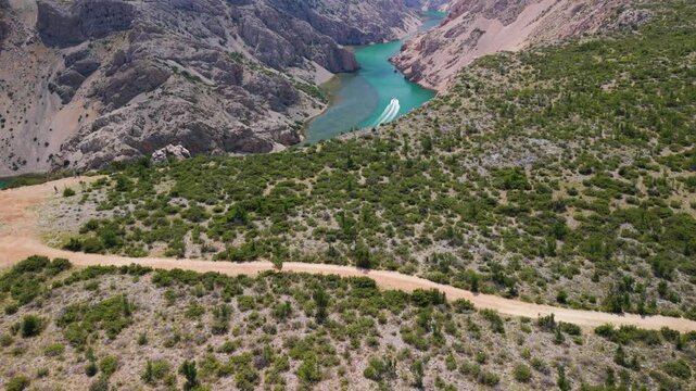 High aerial view of a boat speeding through the emerald Zrmanja River canyon in Croatia