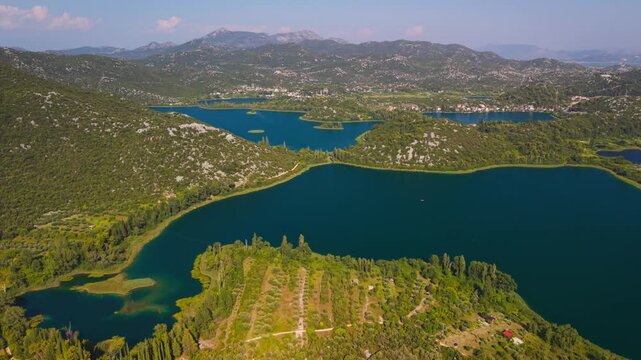 Panoramic aerial view of the vibrant blue Bacina Lakes surrounded by green karst hills near Ploce, Croatia